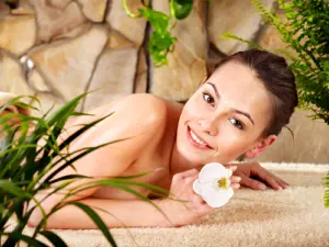 Smiling woman in spa holding flower 